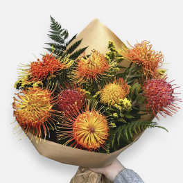 Bouquet of orange and yellow spider chrysanthemums wrapped in brown paper