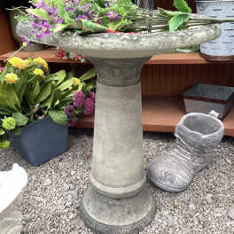 Purple flowers arranged in a stone birdbath planter