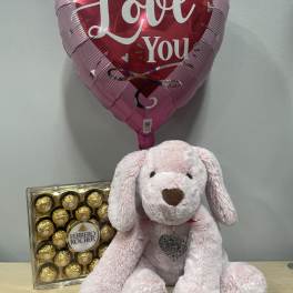 Heart-shaped "I Love You" balloon with a pink plush dog and chocolates