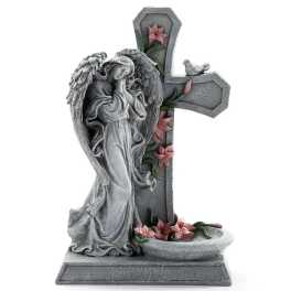 Stone angel statue beside a cross with pink flowers