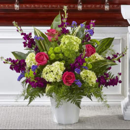Pink roses and purple flowers in a white vase