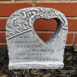 Heart-shaped memorial stone with an engraved quote against a brick wall