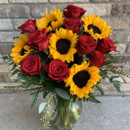 Bouquet of red roses and yellow sunflowers in a glass vase