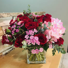 Bouquet of red roses and pink flowers in a clear glass vase