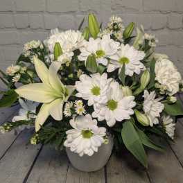 White lilies and daisies arranged in a white vase