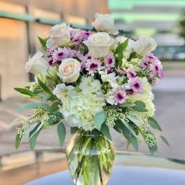 Bouquet of white roses, pink daisies, and hydrangeas in a glass vase