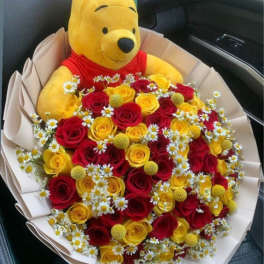 Bouquet of red and yellow roses with a Winnie the Pooh plush