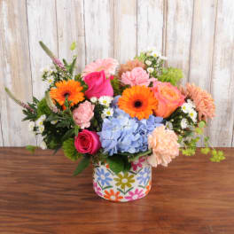 Bright mixed bouquet with pink roses, orange gerberas, and blue hydrangea in a floral ceramic vase