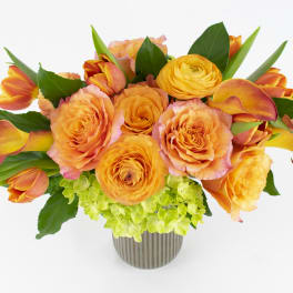 Orange roses and tulips in a striped vase with green hydrangea