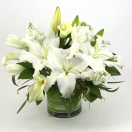 White lilies and calla lilies arranged in a glass vase