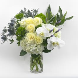 White roses and orchids in a clear glass vase