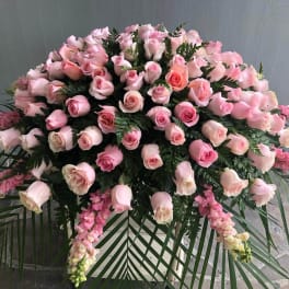 Large pink rose funeral spray with cascading flowers and palm fronds