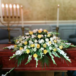 White and yellow rose arrangement on a wooden casket