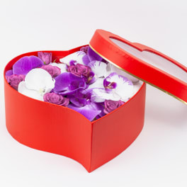 Heart-shaped red box filled with purple and white orchids and small roses