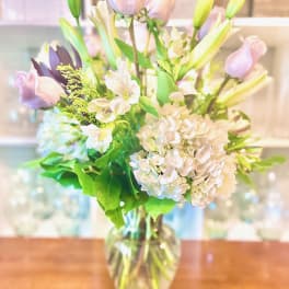 Pastel bouquet of roses, lilies, and hydrangeas in a glass vase