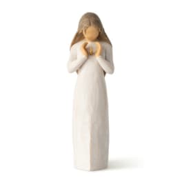 Small angel figurine in a long white dress holding a tiny gold ornament
