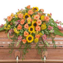 Colorful floral casket spray with sunflowers and peach roses