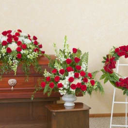 Red carnation funeral arrangements on a casket and wreath stand