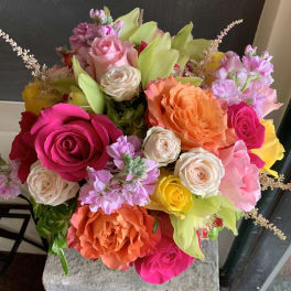 Bouquet of multicolored roses with pale green lilies and pink filler flowers