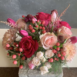 Bouquet of pink and red roses with tulips and berries in a glass vase