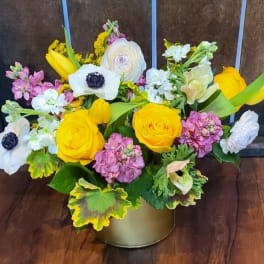 Mixed bouquet of yellow and white flowers in a gold container