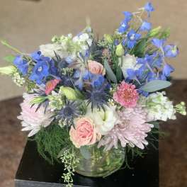 Mixed bouquet of blue, pink, and white flowers in a glass vase