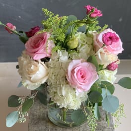 Pink and white roses arranged with hydrangeas in a glass vase