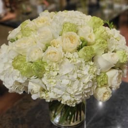 White and pale green bouquet of roses and hydrangeas in a glass vase