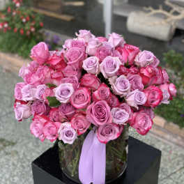 Bouquet of pink and lavender roses in a glass vase with a ribbon