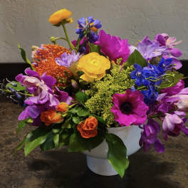 Colorful mixed flower arrangement in a white pedestal vase