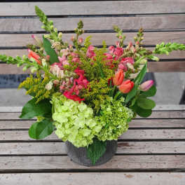 Mixed bouquet in a dark container with pink and green flowers