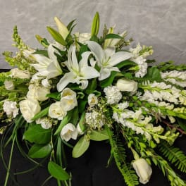 White lilies and roses arranged in a low, elongated spray