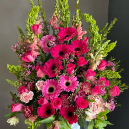 Large pink and green floral arrangement in a white vase