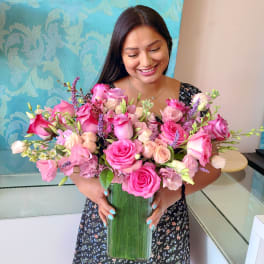 Woman holding a large pink rose bouquet in a tall glass vase