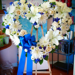 Heart-shaped floral wreath on an easel with a blue ribbon