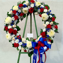 Large floral wreath with red, white, and blue flowers on a stand