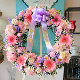 Large pink and lavender floral wreath with a purple bow on an easel