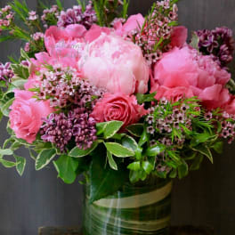 Pink peonies and roses arranged in a glass vase
