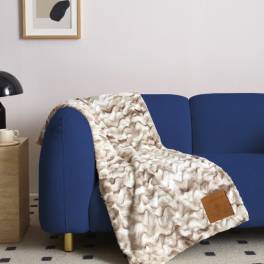 Patterned throw blanket draped over a blue sofa in a living room