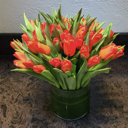 Orange tulips arranged in a dark green vase
