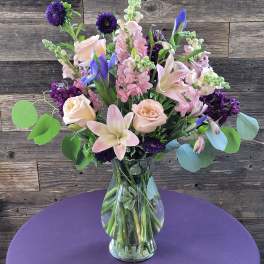 Mixed bouquet of pink and purple flowers in a clear glass vase