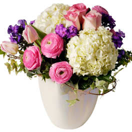 Pink roses, white hydrangeas, and purple flowers in a white vase