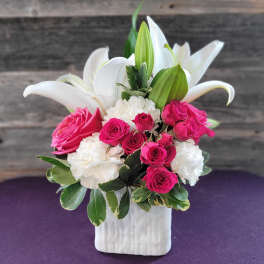 Pink roses and white lilies arranged in a white vase