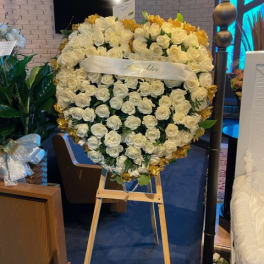Heart-shaped white rose arrangement on an easel with gold accents