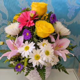 Basket arrangement with yellow roses, pink lilies, and white daisies