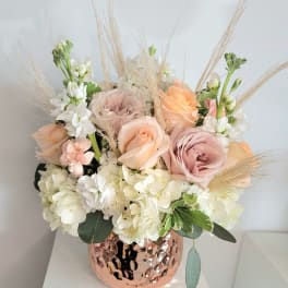Pastel roses and white hydrangeas in a copper vase with dried grasses