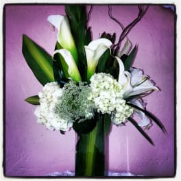 White calla lilies and hydrangeas in a tall glass vase