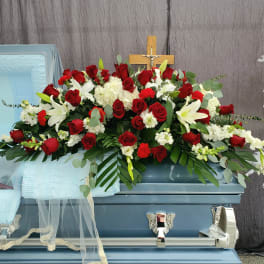Red roses and white lilies arranged on a blue casket
