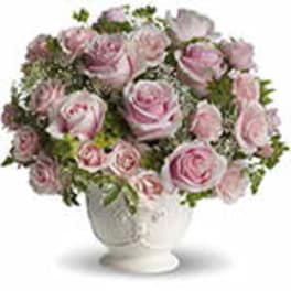 Arrangement of light pink roses in a white ceramic pedestal vase