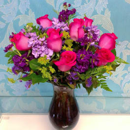 Pink roses and purple flowers arranged in a dark glass vase